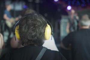 Back of person's head wearing noise cancelling ear muffs in a crowd