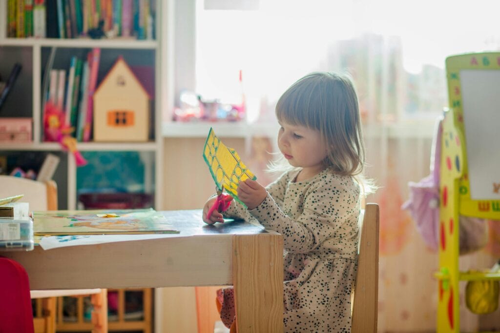 Young child cutting at a table in a pre-school classroom