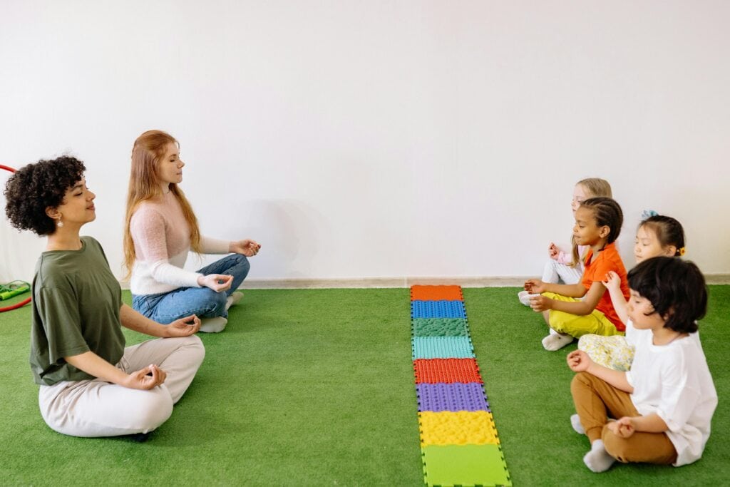 teachers leading a group of young students in meditation